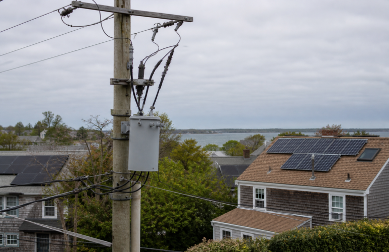 Utility pole and rooftop solar in a coastal New England neighborhood, showing utility interconnection for solar.