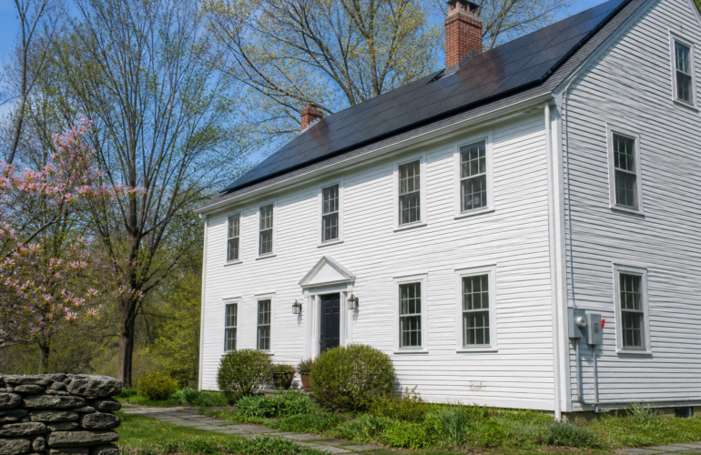 Connecticut colonial home with rooftop solar and an outdoor AC disconnect beside the meter.