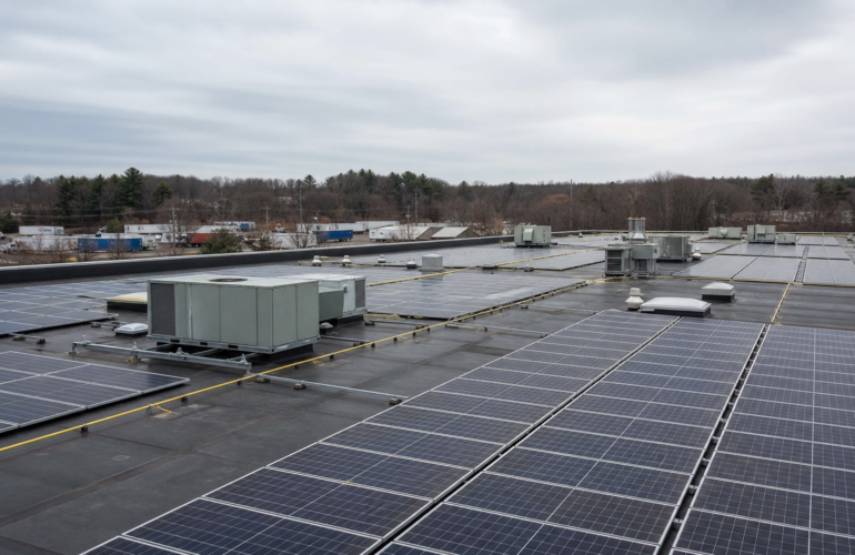 Large commercial flat-roof solar array with HVAC units and maintenance walkways.