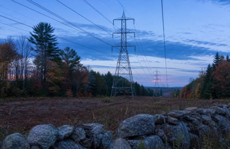 New England high-voltage transmission corridor at dusk, illustrating the ISO-NE cluster study.